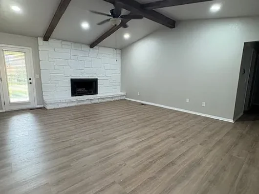 The same living room after renovation, with a brightened stone fireplace, fresh paint and new flooring.
